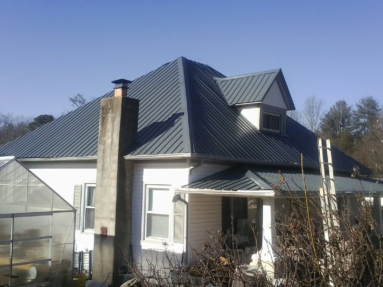 Dark blue standing seam metal roof on a white farmhouse with dormer — Slate & Tile Roof Repair by Roofing Brothers in Shingle Springs