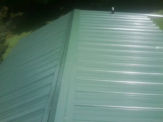 New green metal panels meeting at the ridge of a roof — Flat Roof Repair work by our crew in Shingle Springs