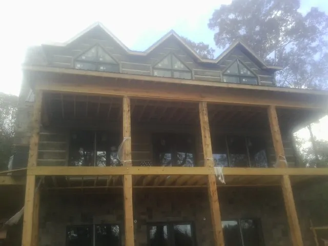Dormers and porch framing on a large log home under construction — Roof Coating work by our crew in Shingle Springs
