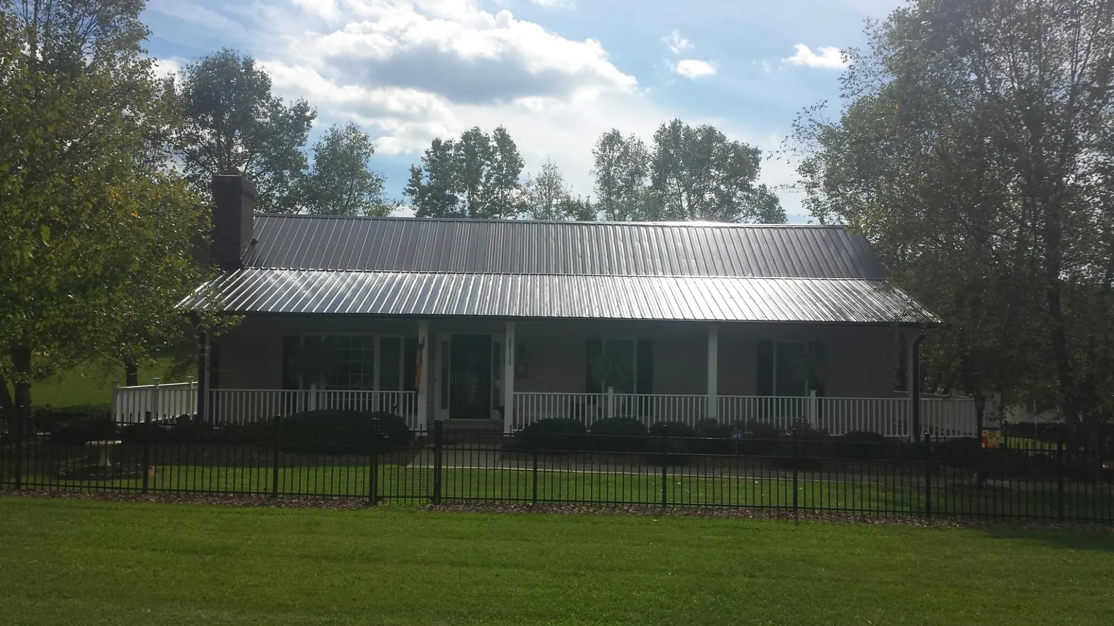 Gray metal roof on a brick ranch with a full width front porch — Gutter Guard Installation work by our crew in Shingle Springs