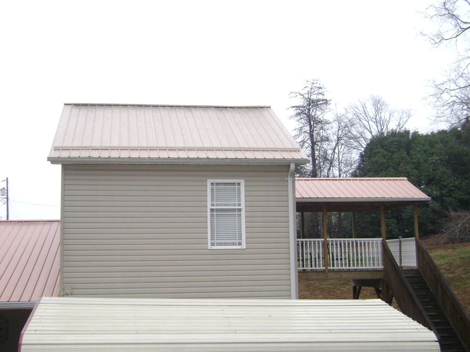 Tan metal roofs on a two story addition and attached porch, from a Roof Replacement job in Shingle Springs