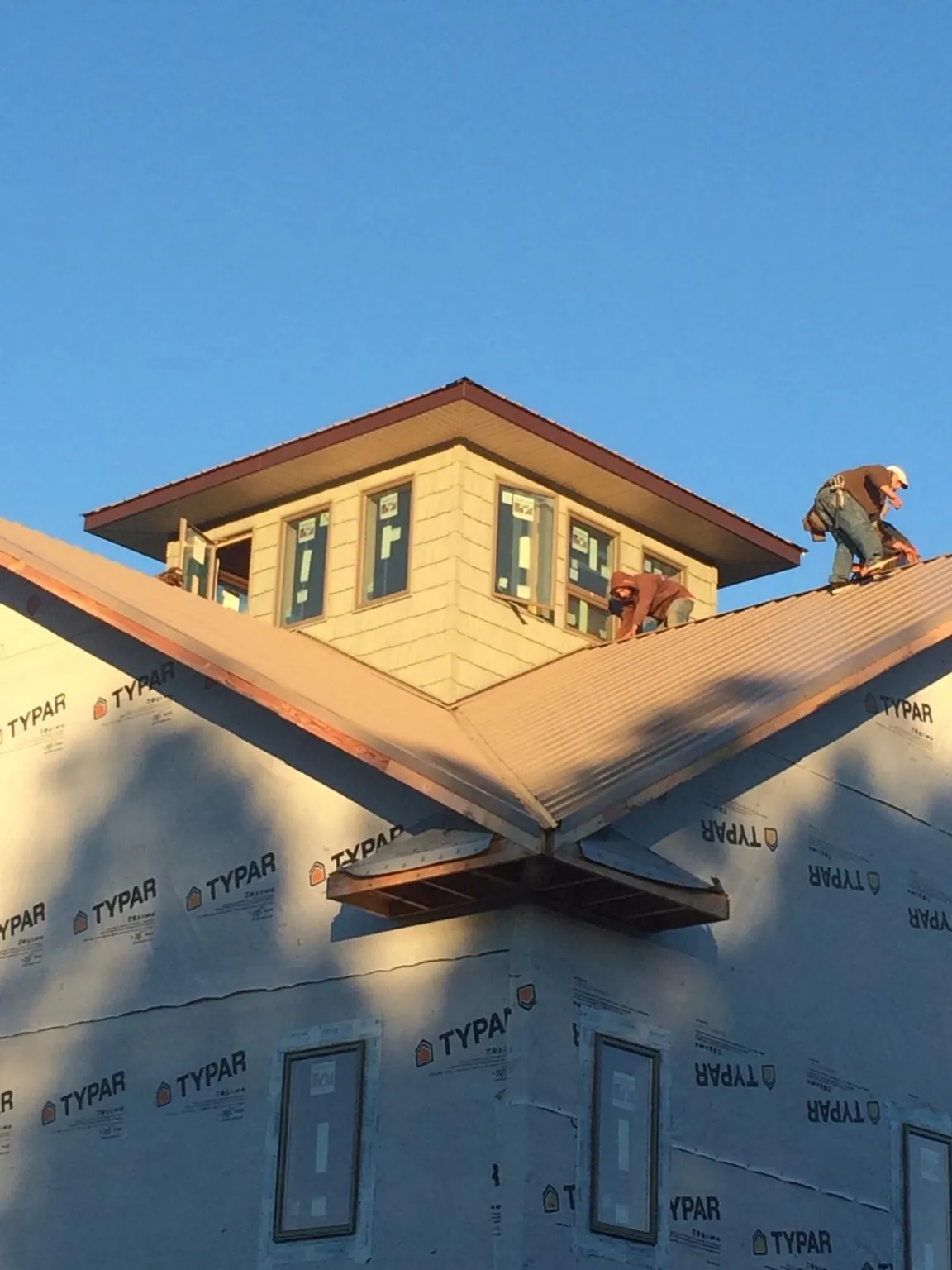 Roofers working around a rooftop cupola on a new metal roof at sunset — Roof Waterproofing in Shingle Springs by Roofing Brothers